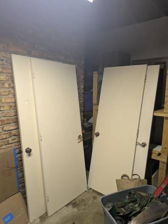 Four white doors with knobs and handles and hinges attached 1