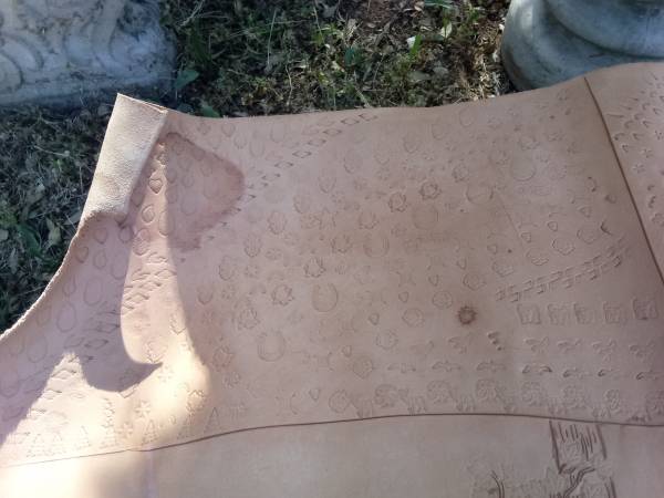 Large piece of leather with pictures carved into it 3 by 4 feet