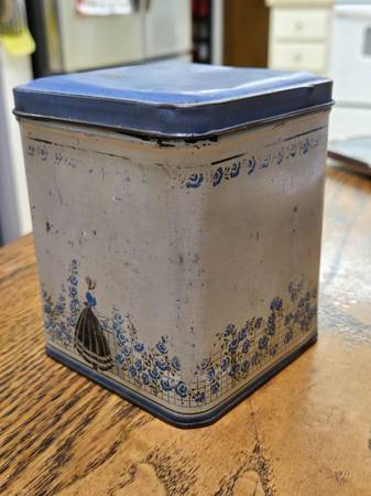 Vintage tin canister with a blue lid and a decorative illustration of 1